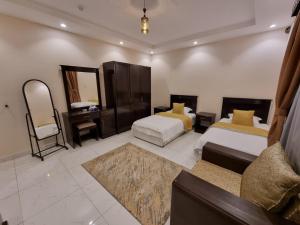 a bedroom with two beds and a vanity and a mirror at شقق نبراس الفارس للشقق المخدومة - اقتصادي in Tabuk