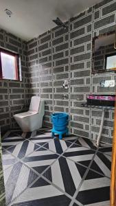 a bathroom with a toilet and a tile wall at Tip Top Pahalgam in Pahalgām