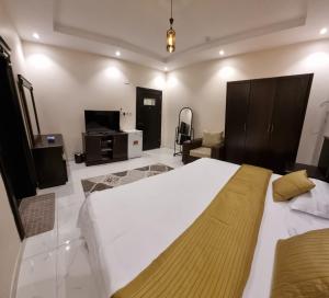 a bedroom with a large white bed and a television at شقق نبراس الفارس للشقق المخدومة - اقتصادي in Tabuk