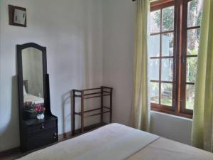 een slaapkamer met een bed, een spiegel en een raam bij Deer Point Hotel Kandy in Kandy