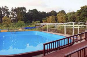 a large blue swimming pool with a metal canopy at Jeju Arbon Resort in Jeju