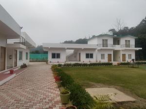 a house with a brick driveway and a grass yard at Great Tiger Resort in Belparāo