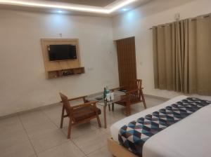 a bedroom with a bed and a table and a tv at Great Tiger Resort in Belparāo