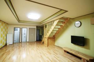 a living room with a staircase and a tv at Jeju Arbon Resort in Jeju