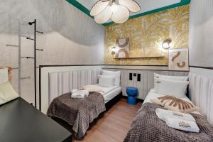 a small room with two beds and a chandelier at DOKI Living - Foodhall & Parking by Downtown Apartments in Gdańsk +14 photos