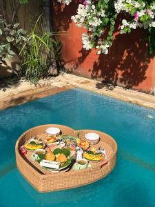 een dienblad met eten op een tafel in een zwembad bij Apalagi Villas in Gili Air