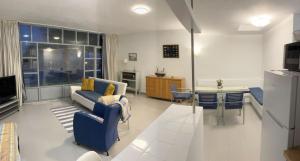 a living room with a blue couch and a kitchen at Casa marea in Puerto Calero