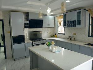 een keuken met witte kasten en een wit aanrecht bij Frontline Homes & Suites 3bedroom Apartment in Lekki
