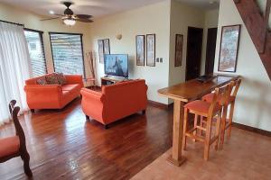 sala de estar con sillas de color naranja y mesa de madera en Picturesque Lakeshore House, en Tilarán