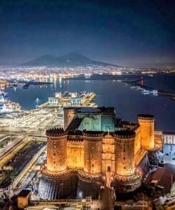 a view of a castle at night with the water at Plebiscito Suite Apartment in Naples