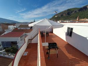 einen Balkon mit einem Sonnenschirm, einem Tisch und Stühlen in der Unterkunft APARTMENT WITH SINGLE ROOMS in Algodonales