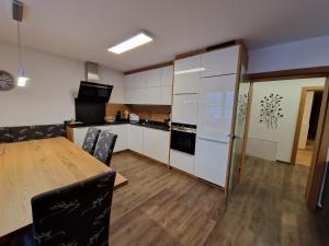 uma cozinha com uma mesa e uma cozinha com armários brancos em Gern Mountain Living Ferienhaus Deutschmann em Sankt Johann im Pongau