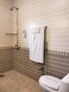 een badkamer met een toilet en een douche met een handdoek bij Riviera Courtyard Guest House Islamabad in Islamabad