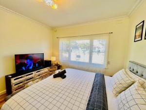 1 dormitorio con 1 cama y TV de pantalla plana en Cosy 4BR Home 15 Minutes Away From Melbourne Airport, en St Albans