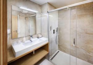 a bathroom with a sink and a shower at Hotel Galeria Thermal Bešeňová in Bešeňová