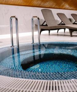 una piscina con 2 sillas al lado en Podina Resort Hotel & Spa, en Ungureni