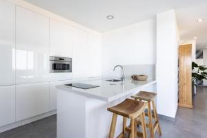 a white kitchen with a counter and two stools at Home Of Tulio in Adeje