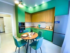 a kitchen with green cabinets and a table and chairs at apartment Tandau Astana in Taldykolʼ