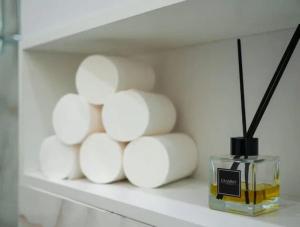 a shelf with a pile of white towels and a perfume at apartment Tandau Astana in Taldykolʼ +1 photo