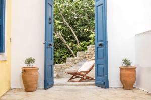an open door with two potted plants and a chair at Myrsini's House in Symi