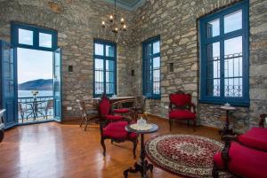 una sala de estar con sillas rojas y una pared de piedra. en Myrsini's House en Symi