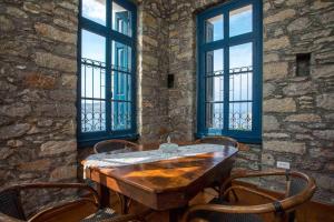 a wooden table and chairs in a room with windows at Myrsini's House in Symi