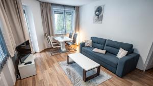 un salon avec un canapé bleu et une télévision dans l'établissement Apartamenty Sun & Snow Nad Potokiem, à Krynica-Zdrój