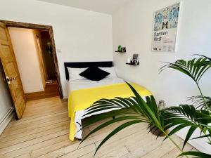 une chambre avec un lit jaune et une plante dans l'établissement Designer Flat in Bethnal Green, à Londres