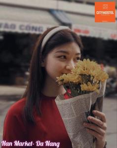 a woman is holding a bouquet of flowers at City Hostel Da Nang in Danang