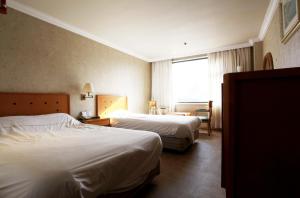 a hotel room with two beds and a window at Jeju Royal Hotel in Jeju