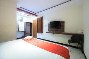 a bedroom with a bed and a tv on the wall at RedDoorz At Kutisari Surabaya in Surabaya