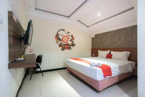 een slaapkamer met een bed, een bureau en een televisie bij RedDoorz At Kutisari Surabaya in Surabaya