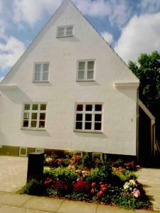 een wit huis met bloemen ervoor bij Smukt, sjælfuldt og charmerende hus midt i Odense. in Odense