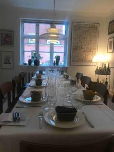 einen langen Tisch mit Tellern und Weingläsern darauf in der Unterkunft Smukt, sjælfuldt og charmerende hus midt i Odense. in Odense