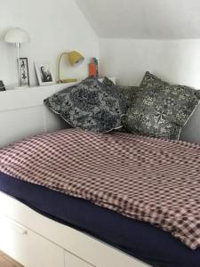 een bed met kussens in een slaapkamer bij Smukt, sjælfuldt og charmerende hus midt i Odense. in Odense