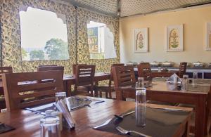 a restaurant with wooden tables and chairs and windows at Ranthambhore Uday Vilas in Sawāi Mādhopur