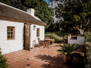mały biały domek z patio i stołem w obiekcie Springfontein Wine Estate w mieście Stanford