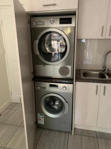 eine Küche mit einer Waschmaschine, einer Waschmaschine und einem Trockner in der Unterkunft Jay's Snug in Knysna