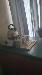 a tea kettle on a tray with cups on a table at Stay at the Ridge in Bloemfontein