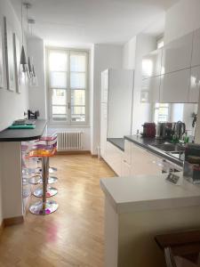 Eine Küche mit weißen Schränken und einer Theke mit Hockern in der Unterkunft CHARMING COMO - Apartment downtown in the pedestrian area with 2 double bedrooms and 2 complete bathrooms a spacious living room and full equipped kitchen in Como