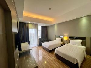 Habitación de hotel con 2 camas y sofá en Livingston Hotel, en Sandakan
