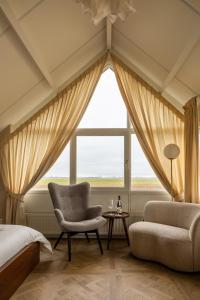um quarto com uma cama, uma cadeira e uma janela em B&B Giethoorn em Giethoorn