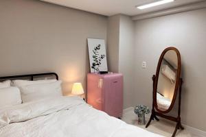 Un dormitorio con una maleta rosa y un espejo en Pet Friendly 301, en Suncheon