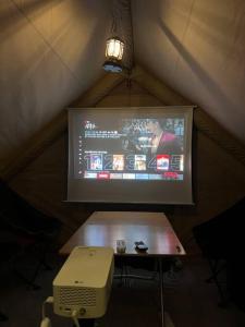 a projection screen in a tent with a table and a television at Pet Friendly 301 in Suncheon