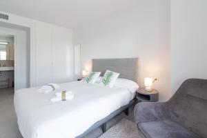 1 dormitorio con 1 cama blanca y 1 silla en Global Properties, Apartamento para 5 personas con terraza y vistas a la piscina, en Canet de Berenguer