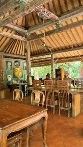 a restaurant with a wooden table and chairs and a person at Bali Telaga Hati Yoga Healing And Retreat Center Hostel in Sanur