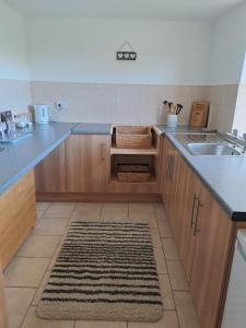 een keuken met houten kasten, een wastafel en een tapijt bij Celtic Minor Cottage in Ystalyfera