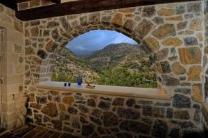 a window in a stone wall with a view of a mountain at Πέτρινο Σπίτι με Θέα Θάλασσα in Achlia