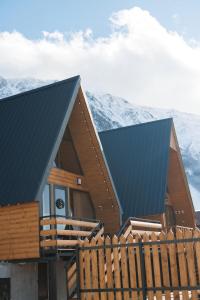 a house with a blue roof with mountains in the background at SMART Via Kazbegi in Stepantsminda