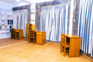 uma sala com mesas, cadeiras de madeira e cortinas em Roamers Inn em Pokhara